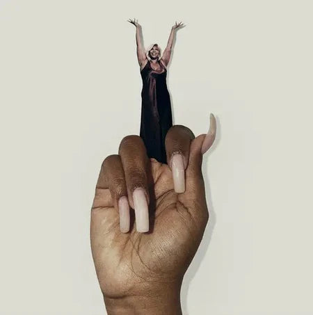Person in a black dress standing on a large hand against a plain background