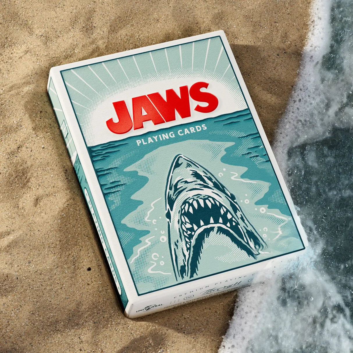 Jaws playing cards packaging on sand with shark illustration