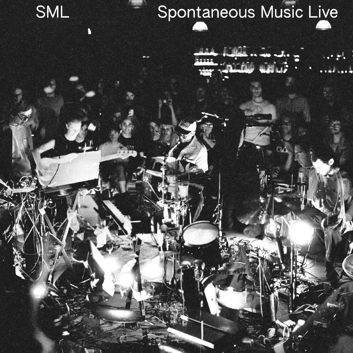 Black and white concert scene with musicians and audience in a dimly lit venue.