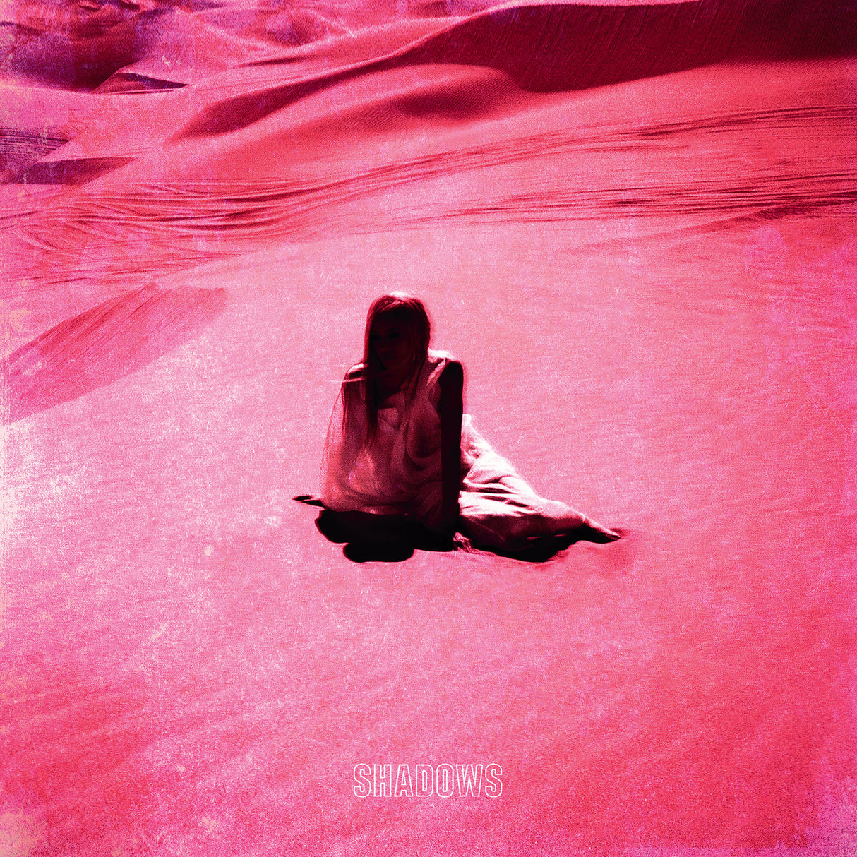 Person sitting on a pink textured surface with 'SHADOWS' text overlay