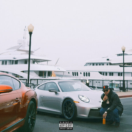 Person squatting next to a white sports car with a large ship in the background
