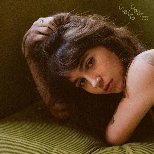 The cover image for Clairo's third studio album 'Charm', featuring Clairo with her eyes closed, resting her head on her hand with a green backdrop.