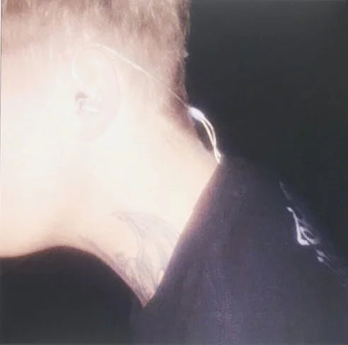 This image features a close-up view of a vinyl record, highlighting its transparent quality. The vinyl, presumably the physical release of Yung Lean's "Frost God LP," displays a minimalistic design with a subtle, diffused image of a person's neck and part of their head in a dark setting, creating a moody and atmospheric look.