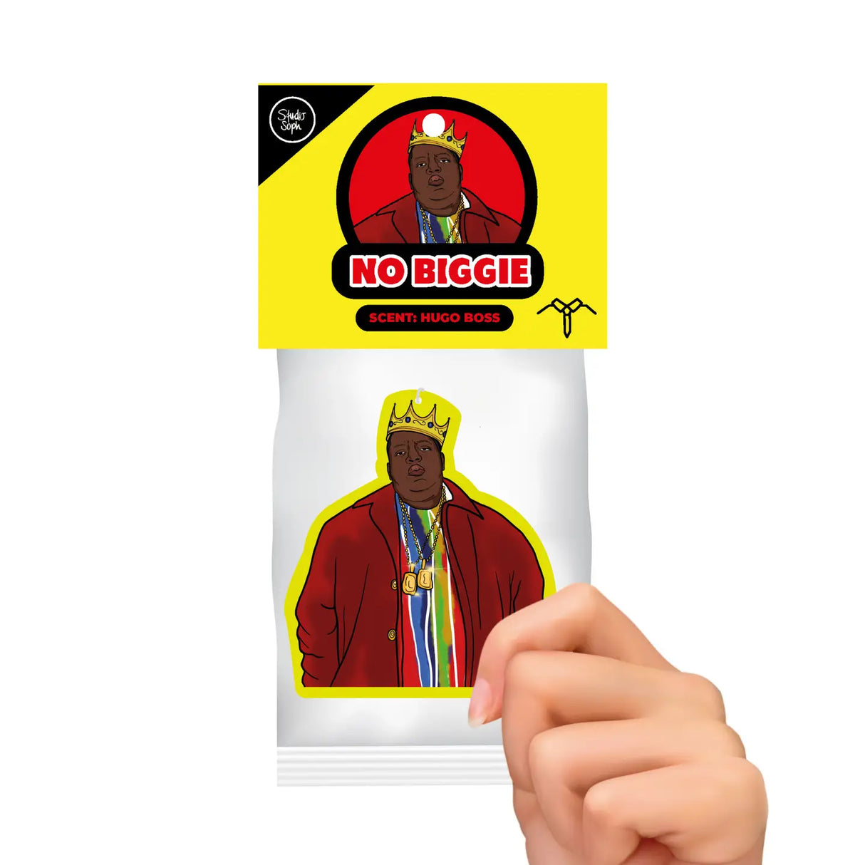 A hand holding a small printed card or sticker featuring an illustrated figure in a red jacket and gold crown, with a bright yellow header that reads 'NO BIGGIE' and 'SCENE: HUGO ROSS'.