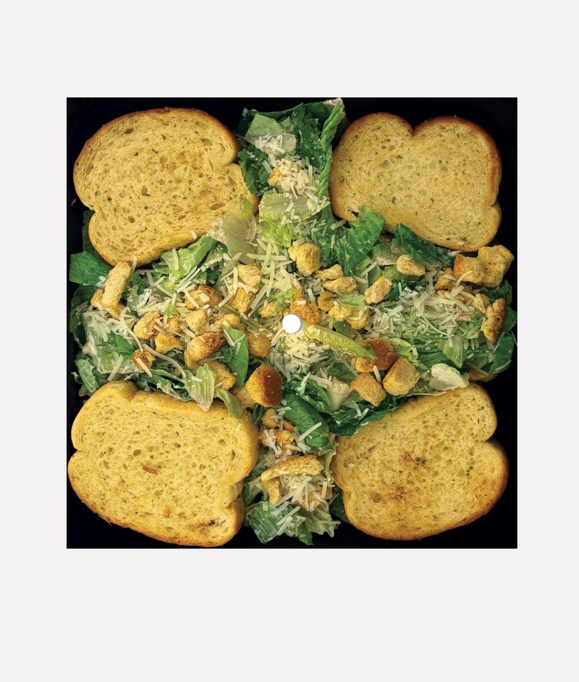 Caesar salad with croutons and dressing on a black background