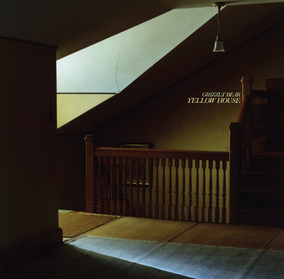 Stairwell with wooden railing and a sign reading 'Yellow House' in a dimly lit room.