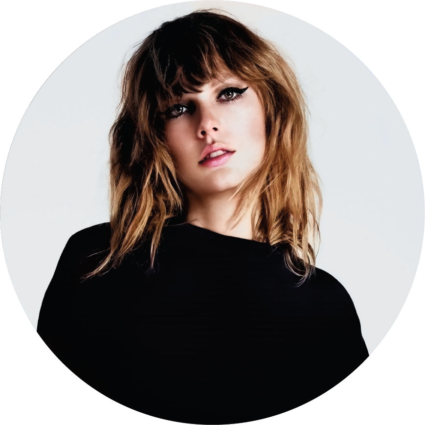 Woman with wavy hair and a black top on a light gray background