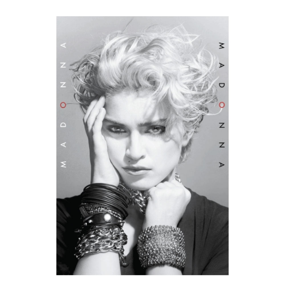 A black and white portrait of Madonna with voluminous curly platinum blonde hair, wearing multiple chunky bracelets and a chain necklace, with the name 'MADONNA' printed vertically on both sides.