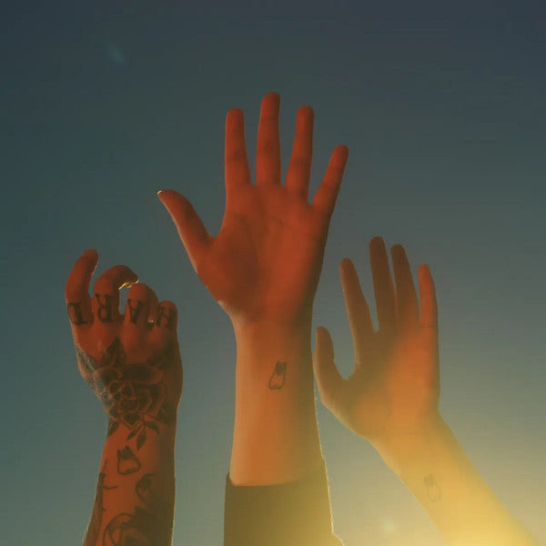 Three hands raised in the air against a blue sky background, symbolizing unity or a communal spirit, possibly related to a music album or event.