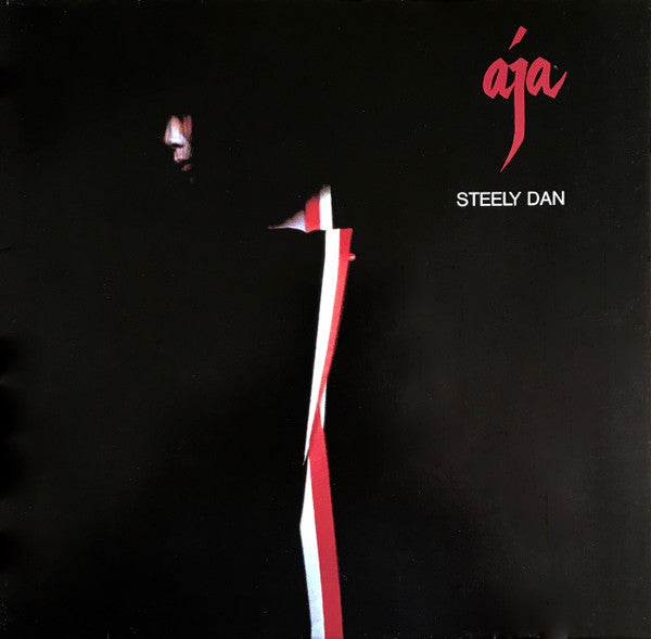 The image features the album cover of "Aja" by Steely Dan. It displays a minimalist design with a black background, punctuated by a striking red and white ribbon that diagonally cuts through the frame, adding a touch of elegance and mystery.