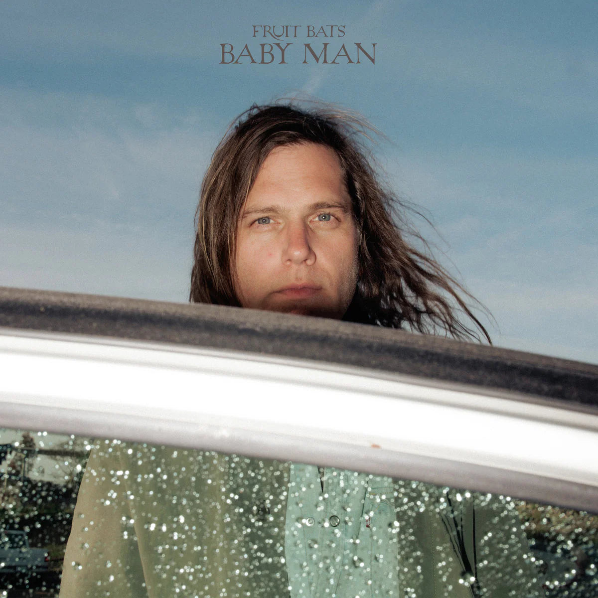 Album cover with a person peeking out from a car window, titled 'Baby Man' by Fruit Bats.