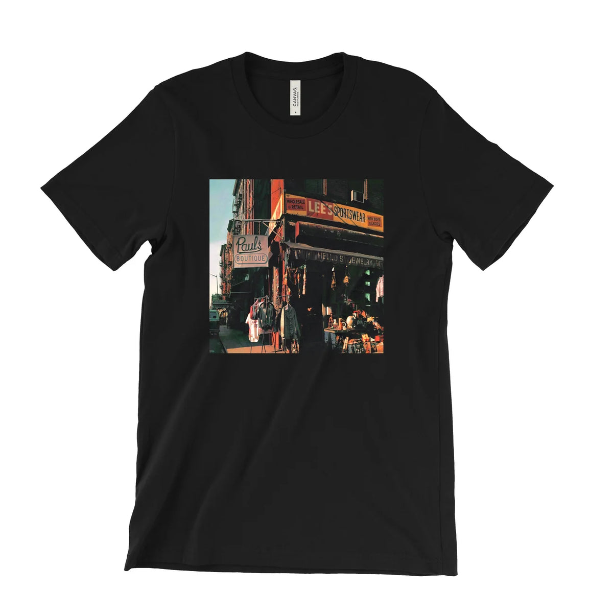 A black short-sleeve crewneck t-shirt featuring a square graphic print of a vintage street scene with a storefront and people, displayed flat against a solid white background.