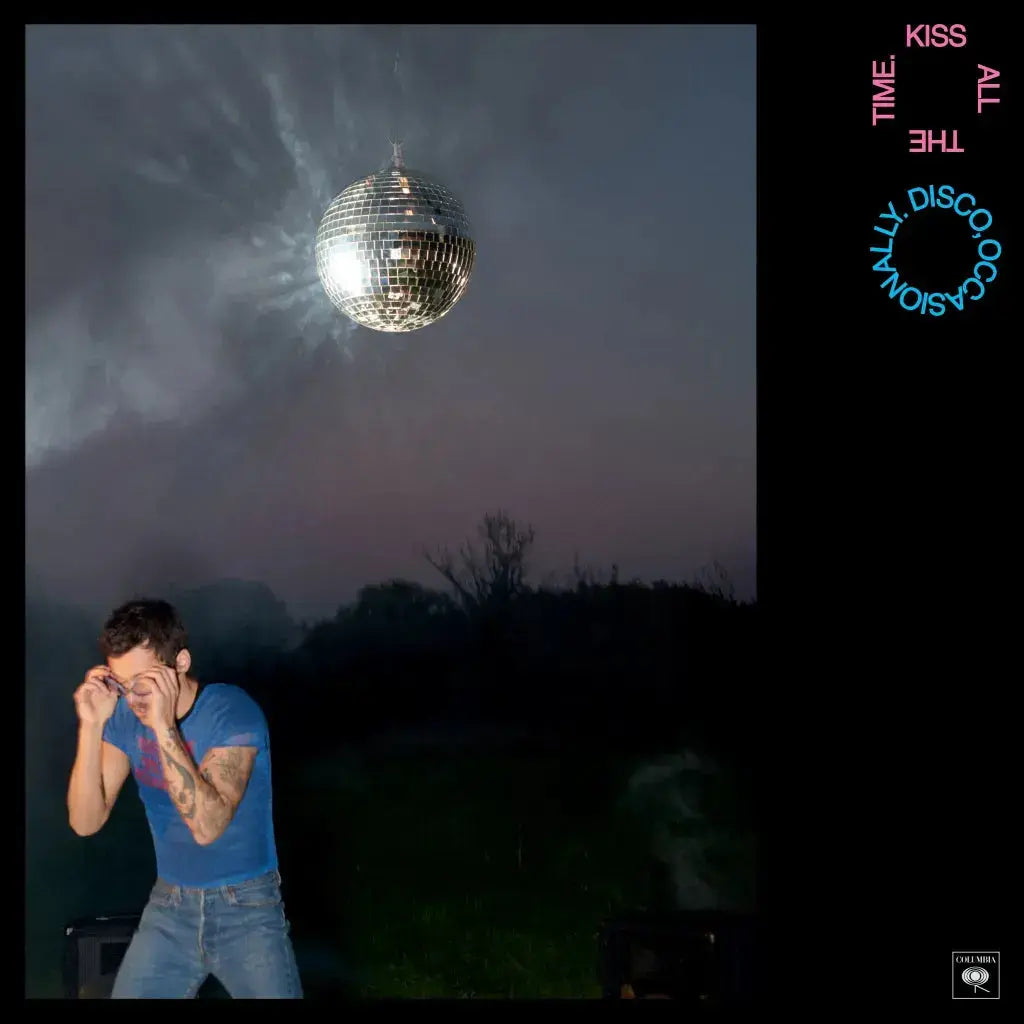 Person in a blue shirt standing under a large disco ball in an outdoor setting with text on the sides.