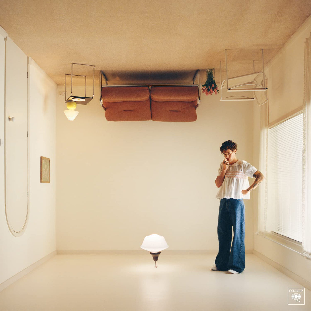 A person standing in a room with low lighting, featuring a record player on the floor and chairs in the background.
