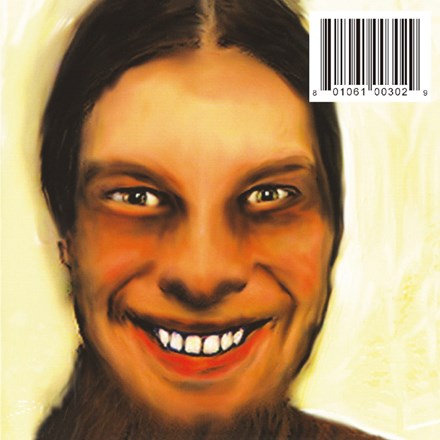 The image shows the cover of the Aphex Twin album 'I Care Because You Do'. It features a portrait of a man with a faint beard and mustache, wearing glasses, with a warm, smiling expression.