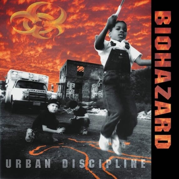 Album cover for Biohazard - Urban Discipline featuring a child jumping over a fire hydrant with a red and orange backdrop, and the band members in the foreground.