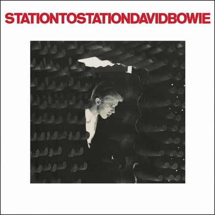 David Bowie peeking from behind a black textured surface with the album title 'Station To Station' written above.