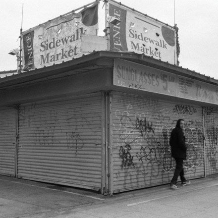 The image shows a recording studio with a sign that reads 'Sidewalk Market', featuring a man walking by with headphones around his neck.
