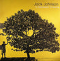 Album cover art for Jack Johnson's In Between Dreams featuring a silhouette of a person standing next to a tree with a yellow background.