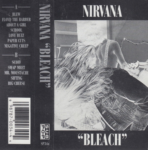This image displays a cassette tape case for Nirvana's album "Bleach". The cover art features a monochrome photograph of a person lying down, adding a raw and simplistic visual element that complements the album's grunge aesthetic.