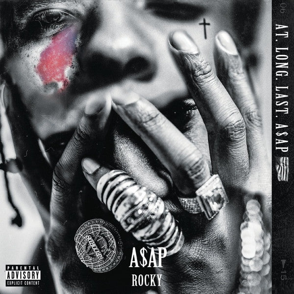 This image features the album cover for "A$AP Rocky - At Long Last 2LP." The cover art is striking, showcasing a close-up photograph of A$AP Rocky with a intense gaze and a red mark on his cheek, complemented by a cross and the artist's logo.