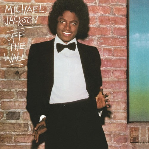 Album cover of Michael Jackson's 'Off The Wall' featuring an image of Michael Jackson in a black tuxedo against a brick wall backdrop, smiling and posing with one hand in his pocket.