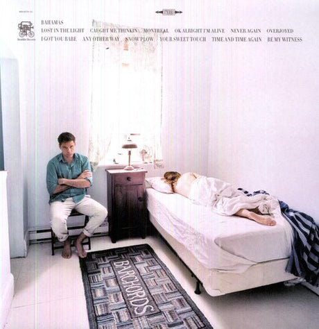 Album cover with a man sitting on a chair and a woman lying in bed, featuring text and album design elements.