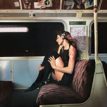 Woman sitting on a train with headphones on, surrounded by posters.