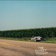 Car on its side on a road next to a cornfield with 'The Sunset Violent' text.
