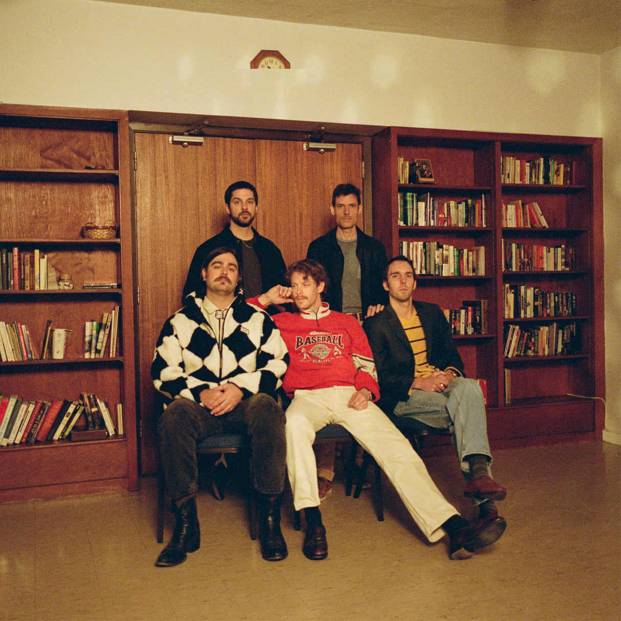 Five men posing together in a room with bookshelves