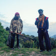 Two individuals standing outdoors with a scenic background