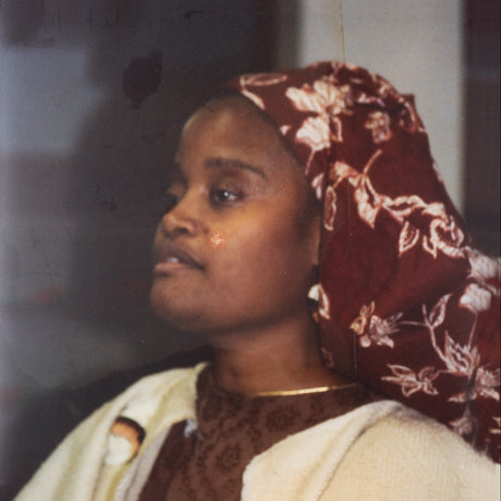 Woman wearing a floral headscarf and white garment, looking to the side.
