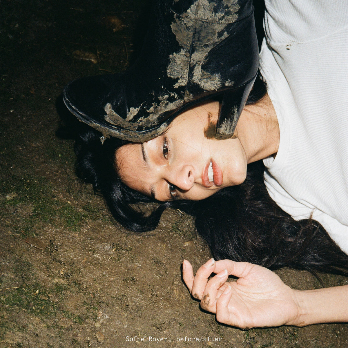 Person lying on the ground wearing a black hat and white garment.