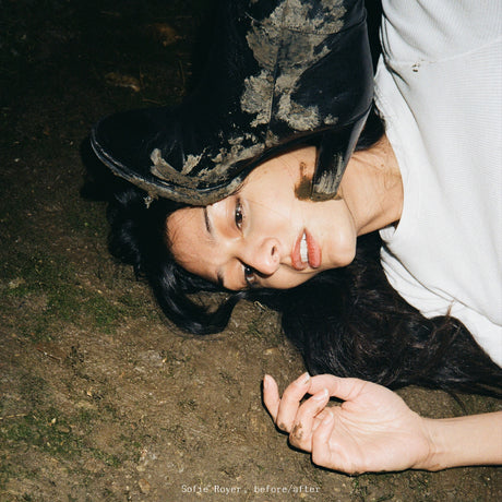 Person lying on the ground wearing a black hat and white garment.