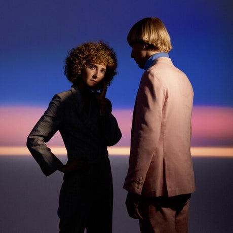 Two people standing against a colorful sky with a gradient of blue, purple, and pink.