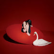Woman sitting on a red platform with a white swan on a red background