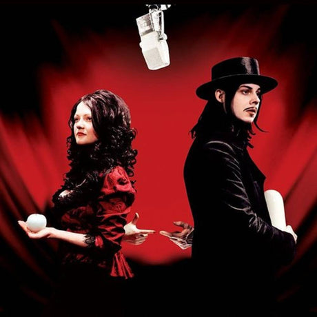 Two people in formal attire with a microphone and red background
