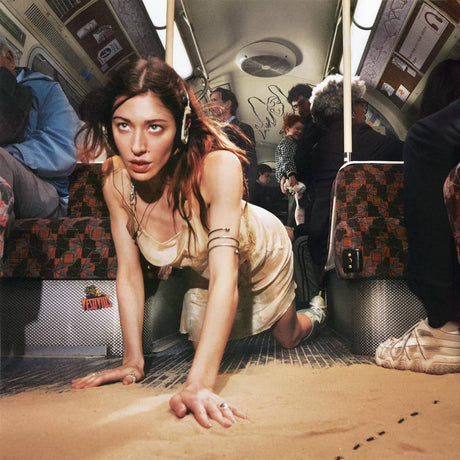 Woman crawling on a sandy floor inside a bus with people around