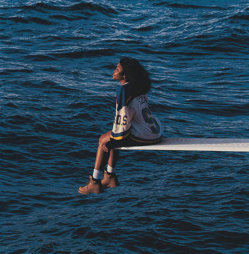 Person sitting on a diving board over a body of water