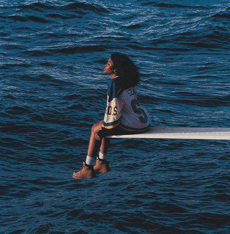 Person sitting on a diving board over a body of water