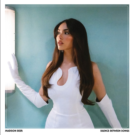 Woman in a white dress with long gloves against a light blue wall