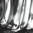 Black and white artistic photograph of multiple distorted, mirrored reflections of a man's face and profile, creating a high-contrast abstract composition.