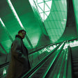 Person standing on an escalator with a green tinted ceiling