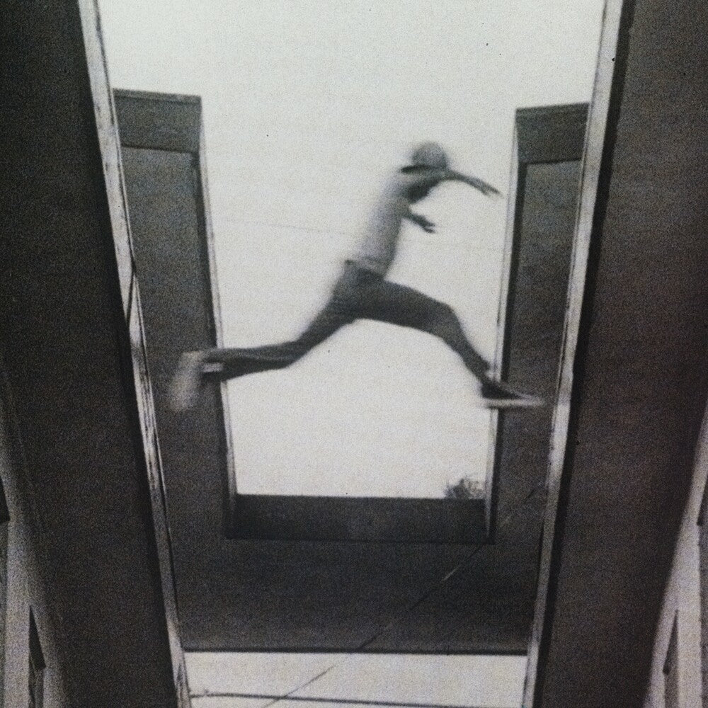 Black and white image of a person running on a tiled floor.