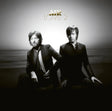 Album cover for Air's 'Love 2' featuring the band members seated on a dark surface against a bright, hazy sky background. The gold 'AIR' logo and 'LOVE 2' title are displayed at the top.