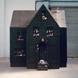 Dark wooden playhouse with small figures and objects on shelves against a plain background