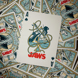 Playing card with 'Jaws' design on a background of more playing cards.