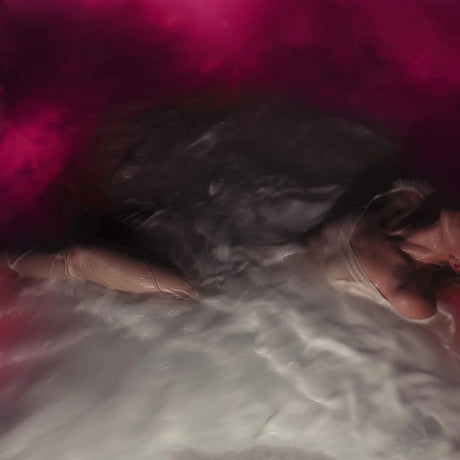 Person lying on a bed with a pink blanket