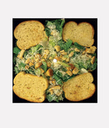Caesar salad with croutons and dressing on a black background