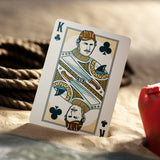 King of Clubs playing card on a sandy surface with ropes in the background